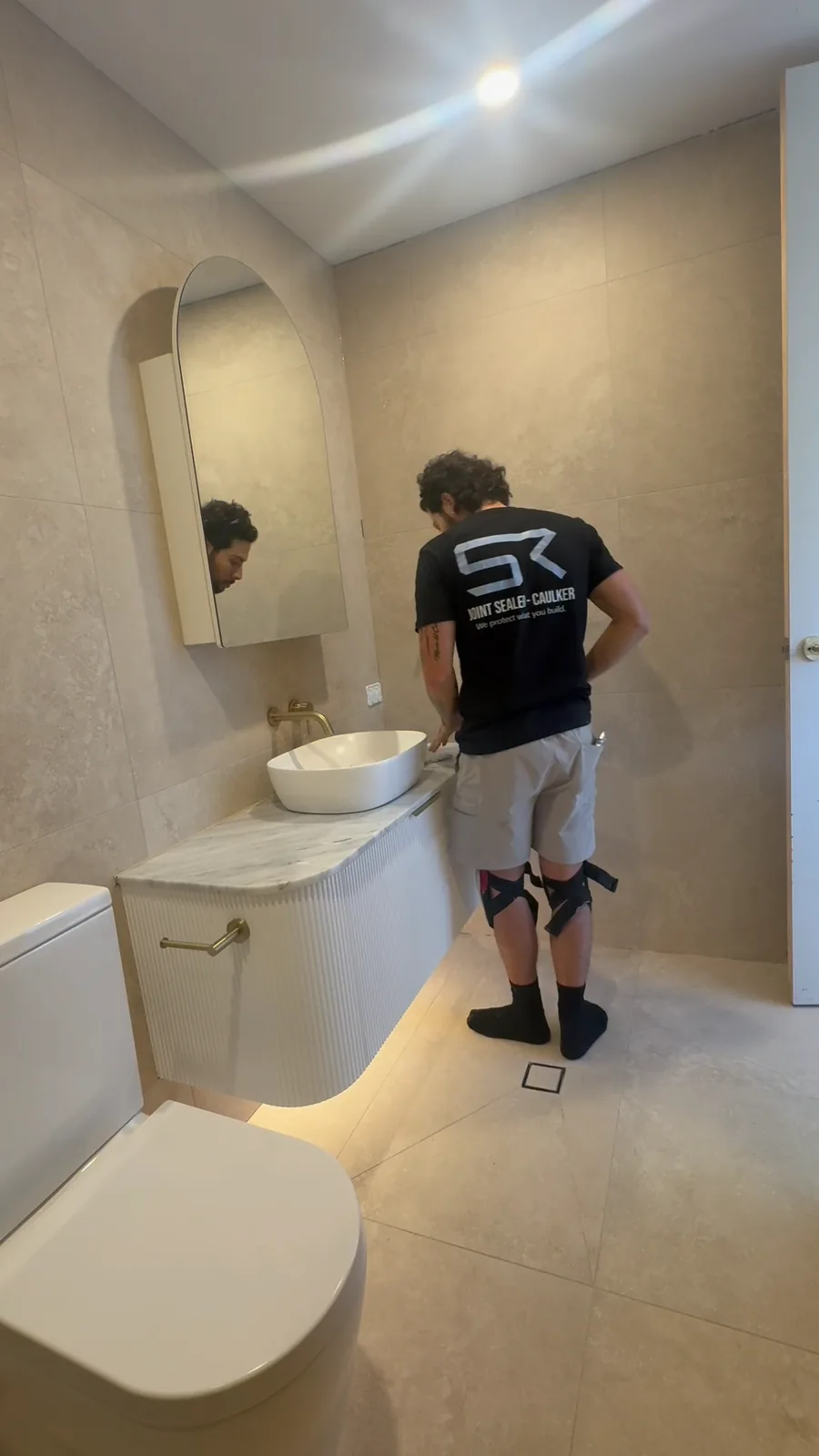 Technician sealing the ceiling junction in a tiled ensuite