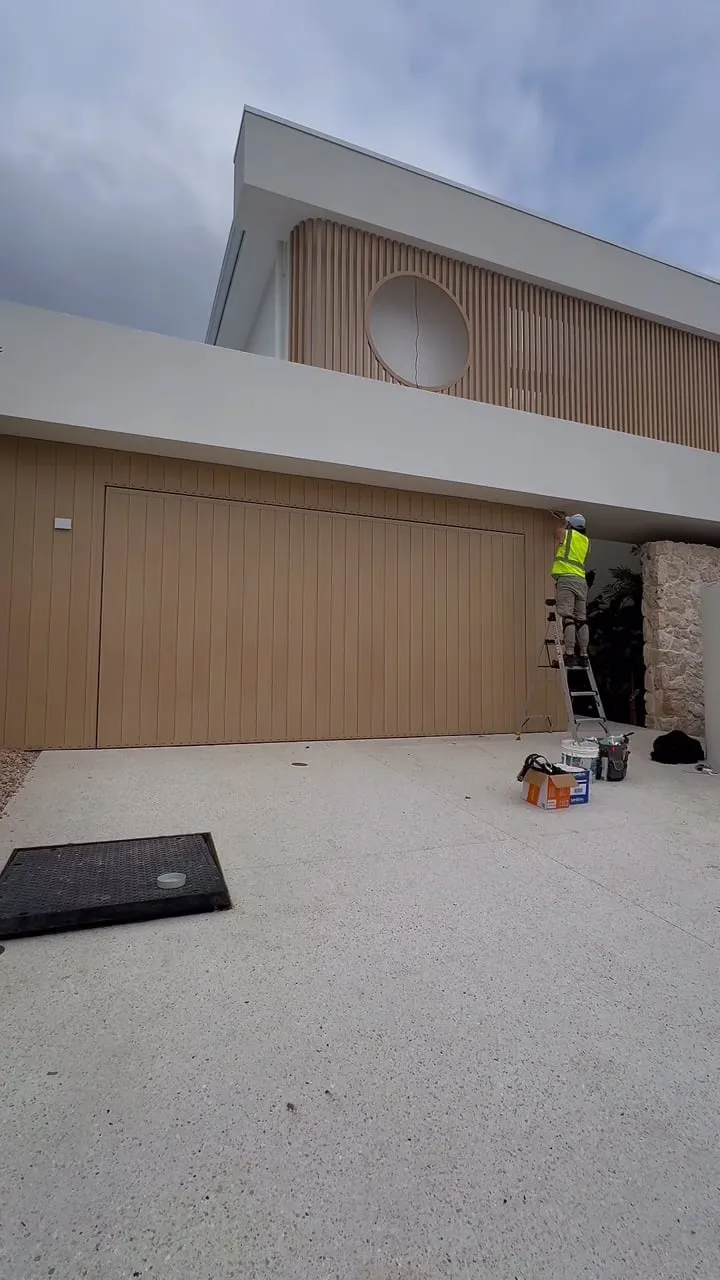 SR Joint Sealer technician on a ladder sealing a timber-clad residential facade